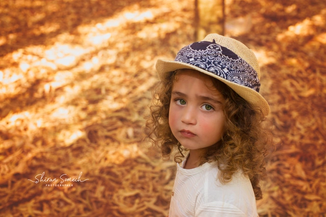 Child in a straw hat with a bandana looking at the camera