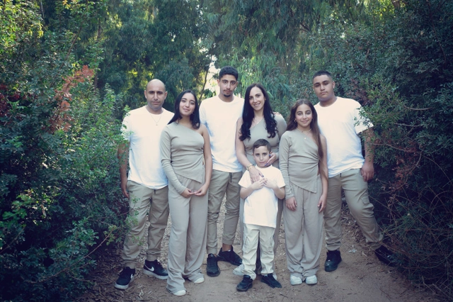 A large family smiling in nature, surrounded by lush green foliage and trees.